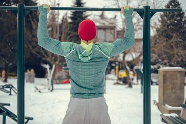 Karlı bir günde dışarıda çene yapan atletik erkek ups