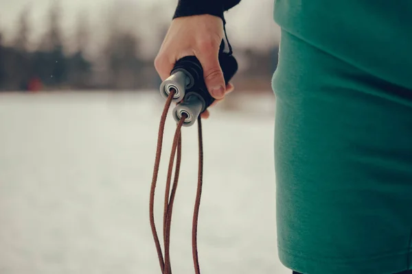 Close up of a man holding jumping rope on the cold snowy day
