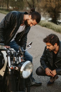 Motosiklet yolda ciddi görünümlü iki erkek arkadaş