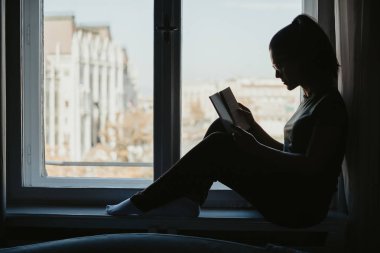 Kitap penceresinde okuma gözlüklü bir kız silüeti