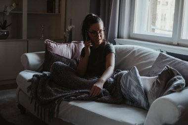 Kanepede oturan ve telefonda konuşurken gözlük ile kız