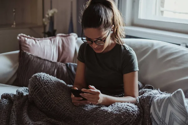 Flicka Med Glasögon Som Sitter Soffan Tittar Mobiltelefon — Stockfoto