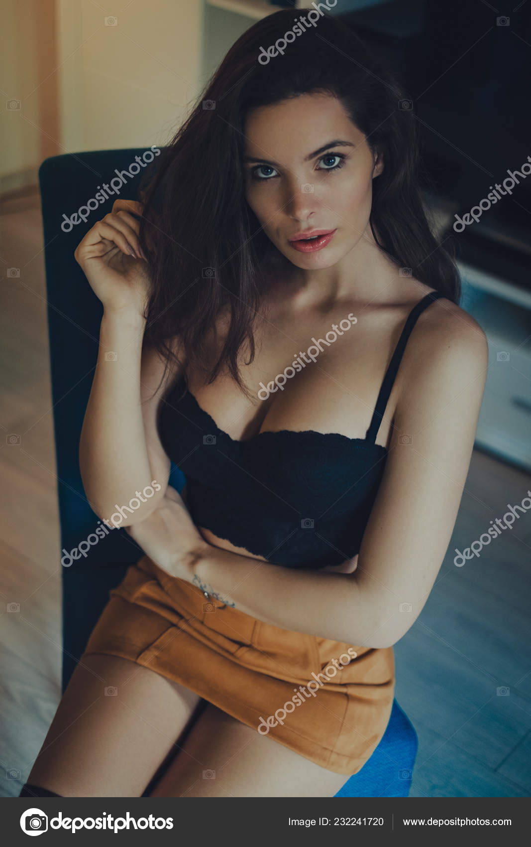 Sexy girl in bra and skirt sitting on a chair Stock Photo by