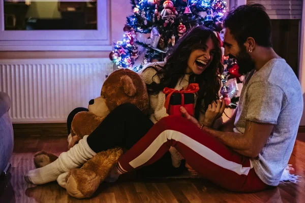 Man giving present to his girlfriend in front of Christmas tree