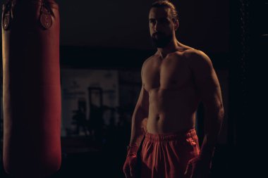 Kum torbası tarafından duran sakallı gömleksiz avcı