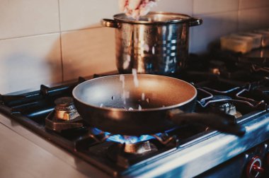 Mutfak Şef bırakarak gaz sobası bir tava içinde soğan dilimlenmiş