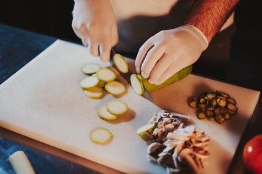 Eldivenler ve taze salatalık bir bıçak ile kesme mutfak Şef