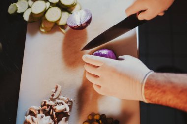 Eldivenler ve soğan bir bıçak ile kesmek için başlangıç mutfak Şef