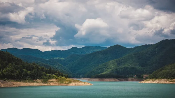 有美丽绿松石水 高山和夏日多云天空的佐薇湖畔 图库照片