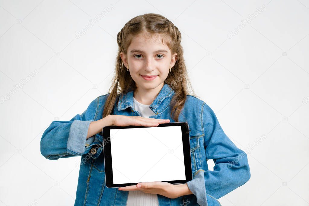A girl with dark hair is holding a tablet with a white place for insertion