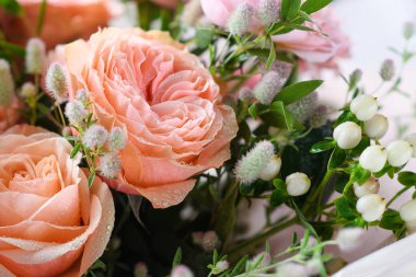 Beyaz böğürtlenli bir buket sprey gül. Gül yapraklarının üzerine su damlaları.