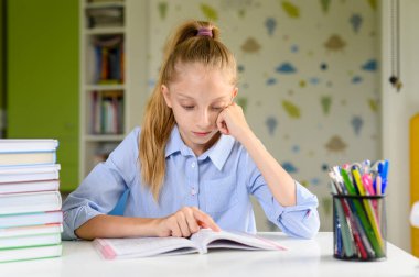 Yorgun bir kız masada bir kitapla oturur ve okur. Onunkini tutar 