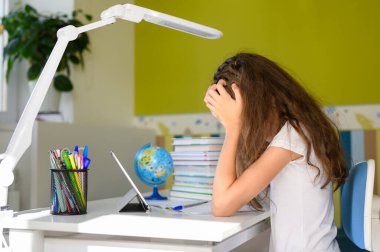 Siyah saçlı bir kız iki eliyle başını tutuyor. Gir