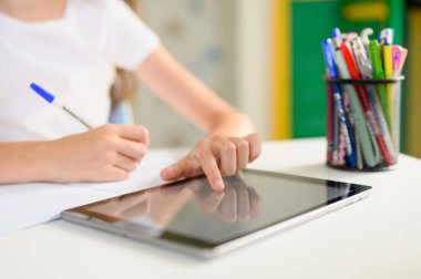 Öğrencilerin elleri tableti kontrol eder. Çevrimiçi ev eğitimi.