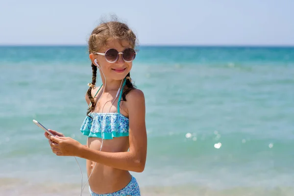 Uma Menina Óculos Sol Fica Praia Ouve Música Smartphone Uma — Fotografia de Stock