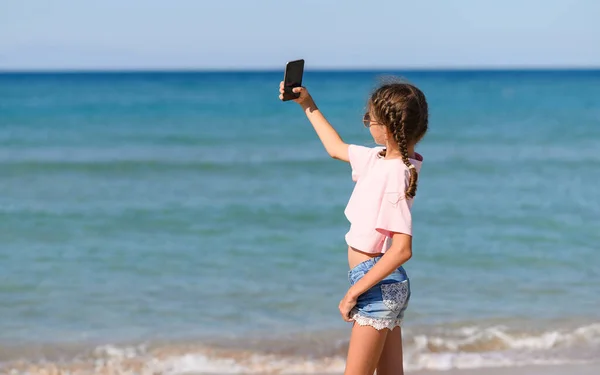 Dziewczyna Stoi Plaży Nad Morzem Robi Sobie Selfie Nowoczesna Dziewczyna — Zdjęcie stockowe