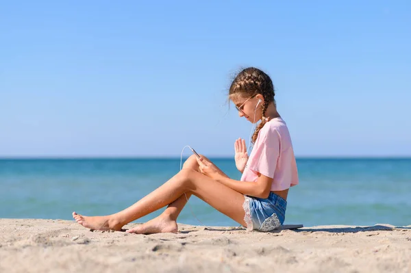 Kız internet üzerinden deniz kenarında iletişim kuruyor. Tatilde online iletişim.
