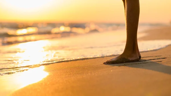 Legs against the backdrop of a beautiful sunset on the seashore. Focus on the legs. There is room for text.