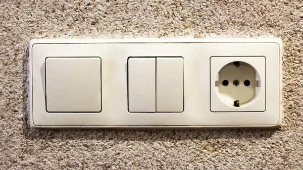 Electric light switch and socket on the empty wall, electrical power socket and plug switched, object