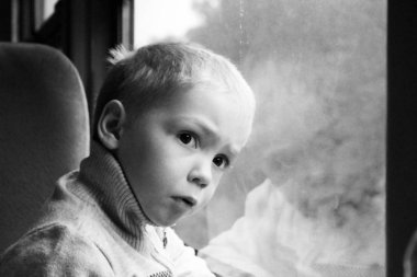 Sevimli küçük çocuk çocuk şehir tren pencereden dışarı bakarak beyaz tişört. Çocuk demiryolu ile seyahat. Genç yolcusu. Nesne.