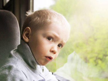 Sevimli küçük çocuk çocuk şehir tren pencereden dışarı bakarak beyaz tişört. Çocuk demiryolu ile seyahat. Genç yolcusu. Nesne.