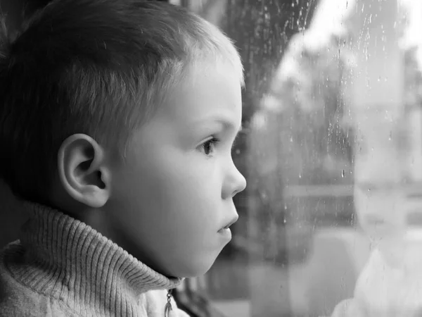 Lindo Niño Con Una Camiseta Blanca Mirando Ciudad Por Ventana — Foto de Stock