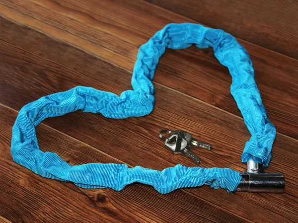 blue bike lock on wooden background, shape heart