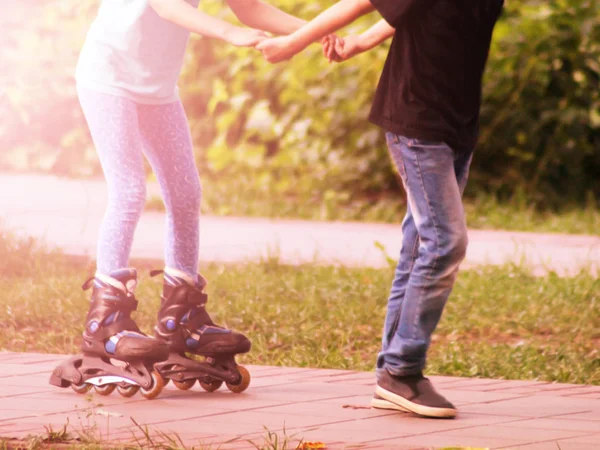 Boy teaches girl to roller skate at sunset, toned