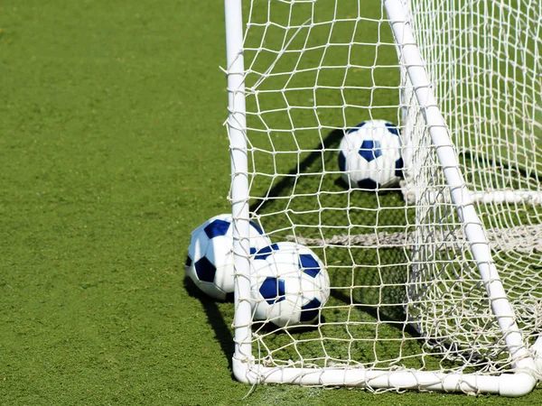 Football goal and balls on a green field, sport