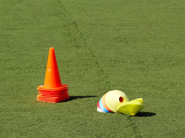 Plastic chips and cone for football training. Sports playground with markings on an artificial lawn on a soccer field.