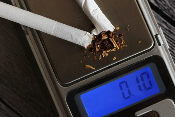 Broken cigarettes on electronic scales, dangers of smoking