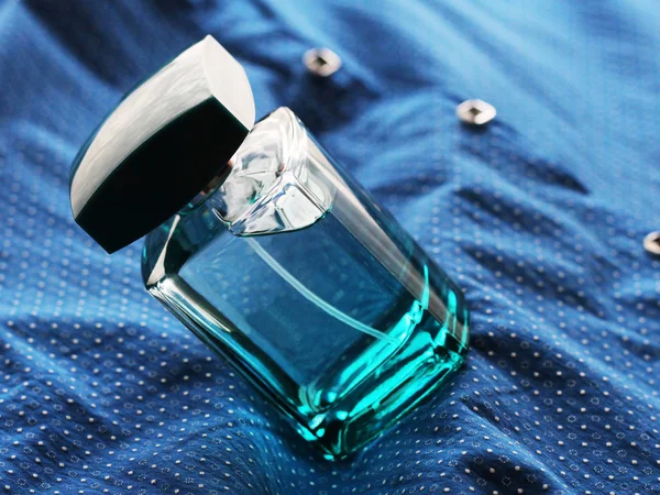 Zielone perfumy męskie w pięknej butelce na niebieskim tekstyliach — Zdjęcie stockowe