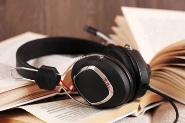 Ses kitabı konsepti. Kulaklıklar ve eski kitaplar ahşap masanın üzerinde..