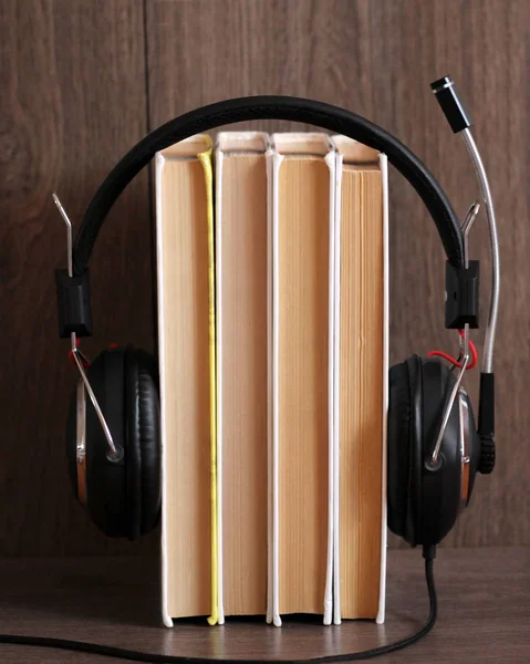 オーディオブックのコンセプト。木製のテーブルの上にヘッドフォンや古い本. — ストック写真