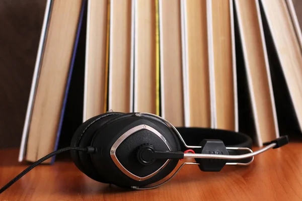 Concepto de audio libro. Auriculares y libro viejo sobre mesa de madera. —  Fotos de Stock