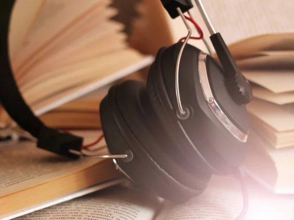 Concepto de audio libro. Auriculares y libro viejo sobre mesa de madera. —  Fotos de Stock
