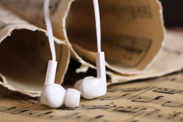 Білі навушники та старі паперові нотатки — стокове фото