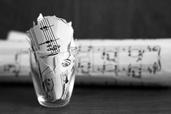 Notas musicais rasgadas em um copo, pedaços de papel — Fotografia de Stock