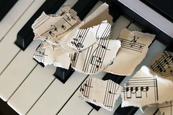 Gescheurd muzikale noten, stukjes papier op piano — Stockfoto