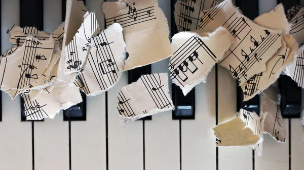 Gescheurd muzikale noten, stukjes papier op piano — Stockfoto