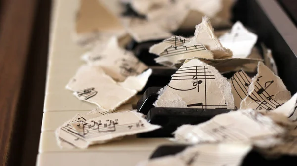 Notas musicales desgarradas, trozos de papel sobre piano — Foto de Stock