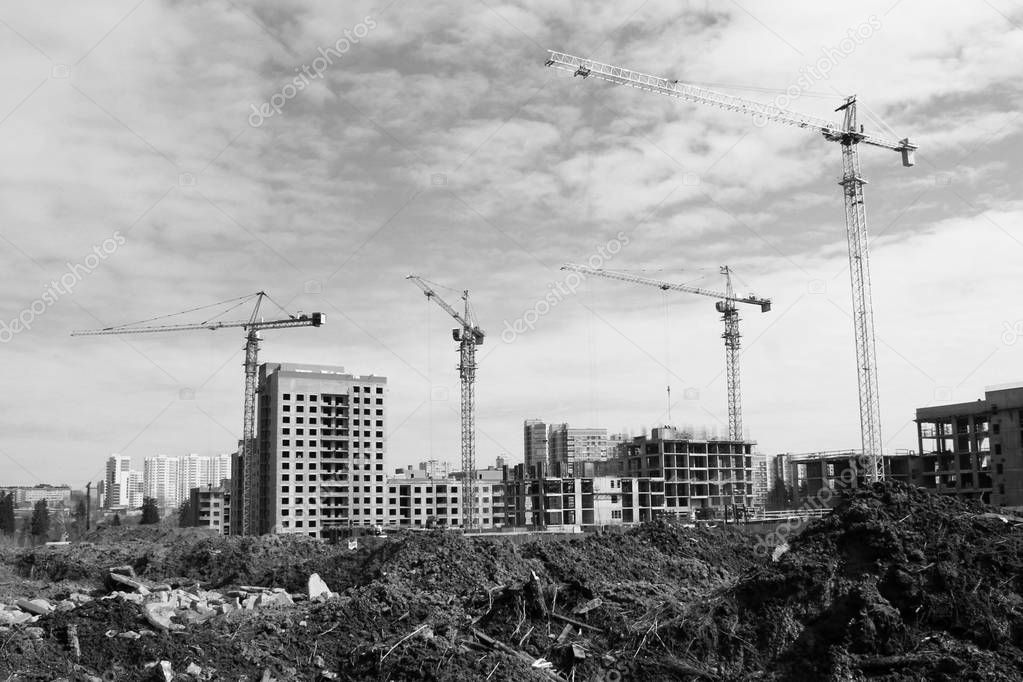 Construction site tower cranes against sky, black and white