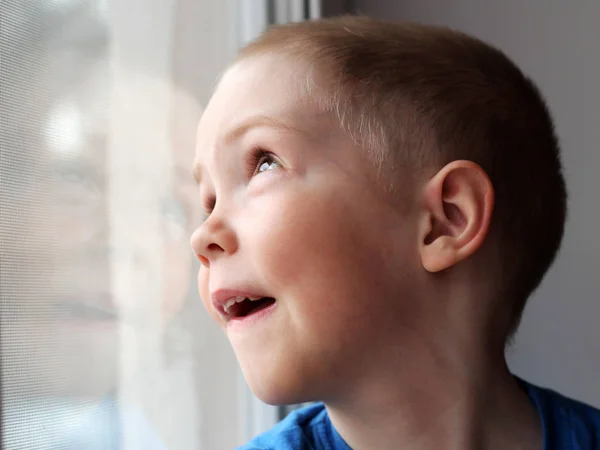 Retrato de un niño alegre mirando por la ventana — Foto de Stock