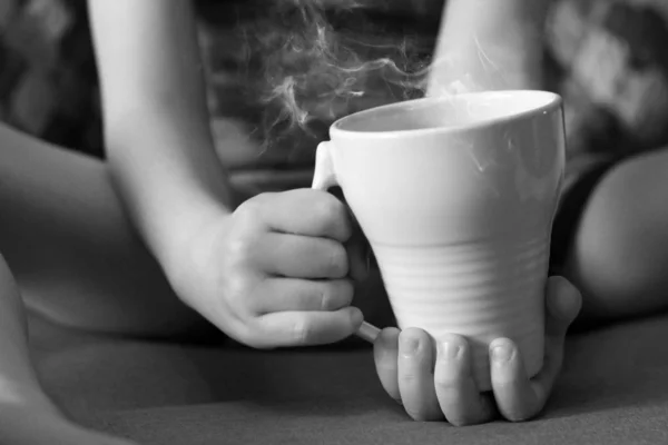 子供の手に紅茶のカップ, 黒と白 — ストック写真