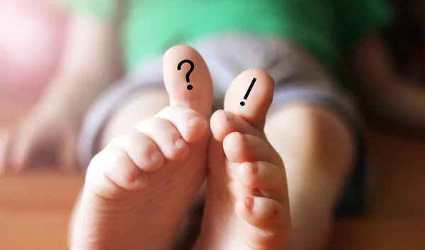 Question and exclamation marks painted on fingers, children\'s feet