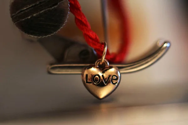 Red string with a heart of gold and a sewing machine