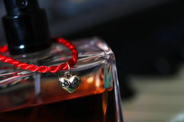 Red thread with gold heart pendant and women's perfume — Stock Photo, Image