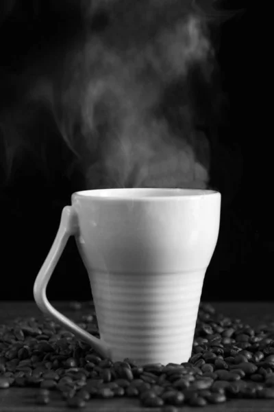 Café noir en tasse blanche et grains de café sur fond noir. Vapeur . — Photo