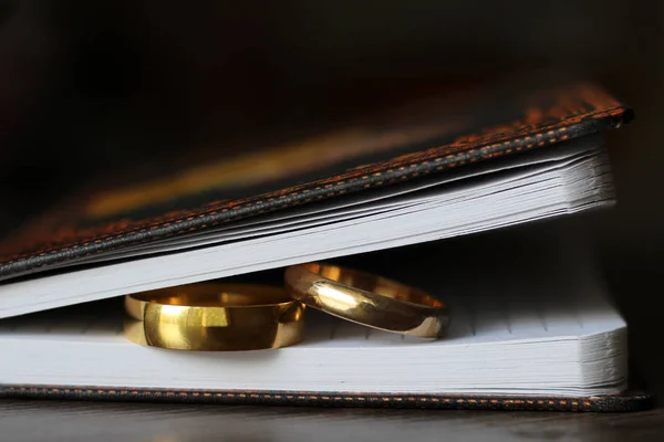 Dois anéis de casamento de ouro e um caderno de papel — Fotografia de Stock