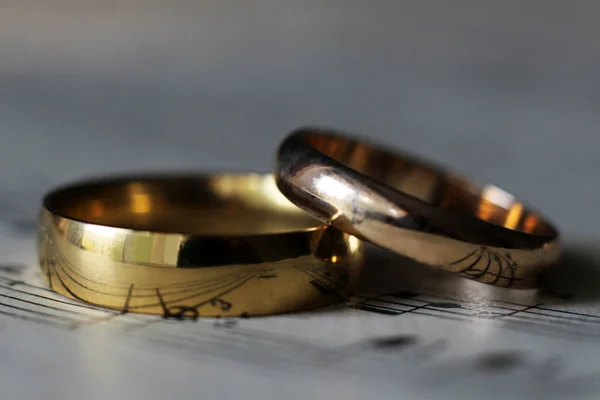 Two wedding rings and old musical notes — Stock Photo, Image